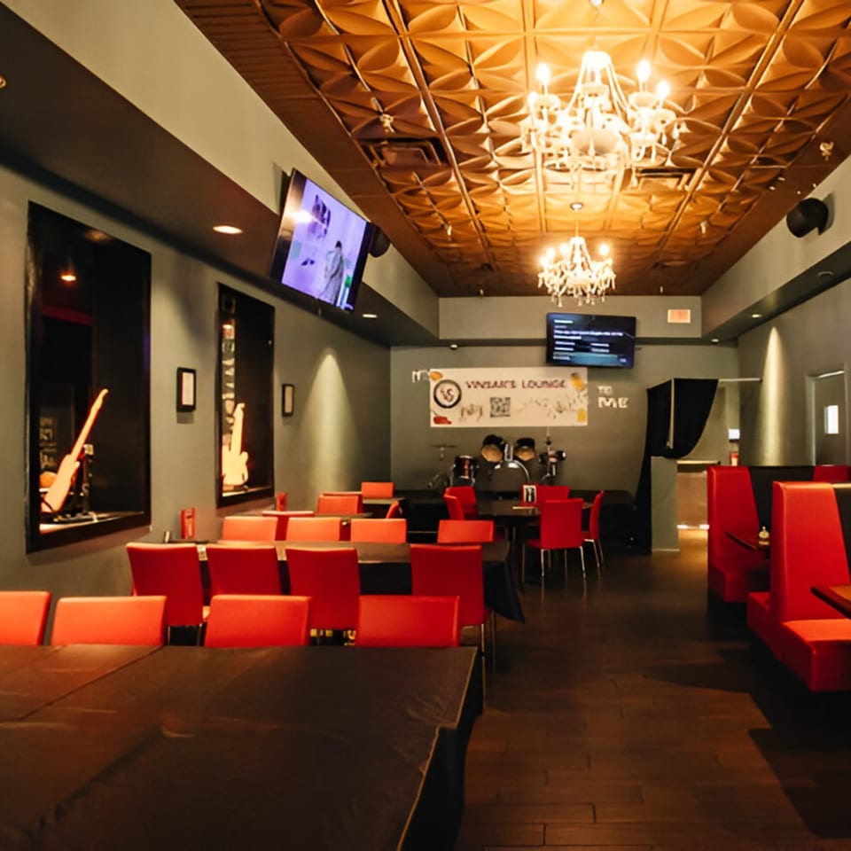 Vinsar's Lounge interior with red chairs, dark tables, chandeliers, and guitars displayed in wall cutouts.